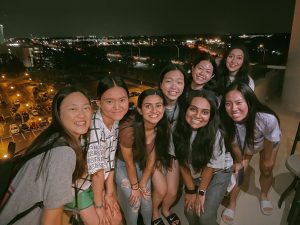 A small group of young people stand on a balcony.