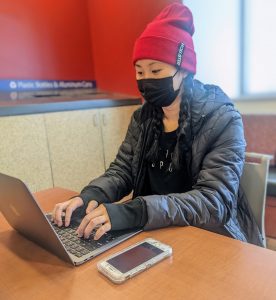 One student sitting with a laptop and cellphone.