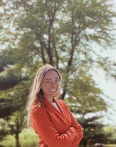 A portrait of a young woman standing outdoors.