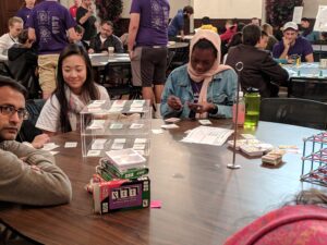 Two girls and an adult smile while working on a puzzle.