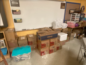 A photo of a classroom wall with about a dozen boxes stacked up.