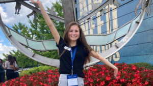 A girl stands in front of a globe structure
