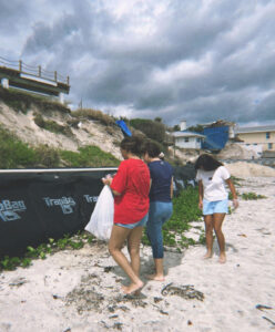 Three students look for litter on a beach. 