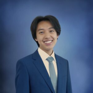 a portrait of a young person wearing a dark blue suit with a light blue tie